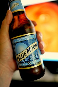 A hand holding a bottle of Blue Moon beer.